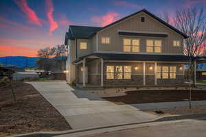 View of front of house featuring concrete driveway, a porch, board and batten siding, and roof with shingles