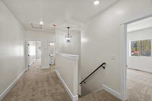 Hallway featuring an upstairs landing, light colored carpet, and recessed lighting