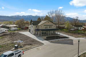 View of front facade featuring a mountain view, covered porch, a residential view, and stone siding