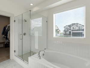 Full bathroom featuring a walk in closet, a garden tub, and a shower stall