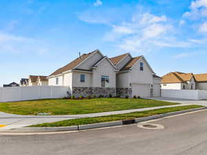 View of front of home featuring board and batten siding, stone siding, concrete driveway, and a residential view
