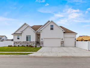 View of front of house with board and batten siding, stone siding, driveway, and a shingled roof
