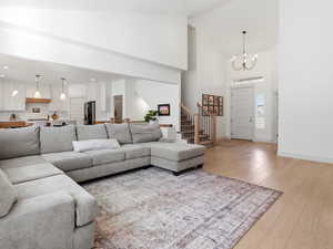 Living room with light wood finished floors, a chandelier, and lofted ceiling