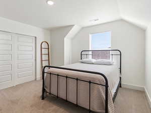 Bedroom featuring light colored carpet, lofted ceiling, and a closet