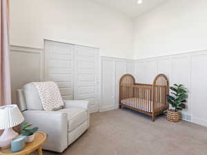 Carpeted bedroom with a decorative wall, a wainscoted wall, a nursery area, and recessed lighting