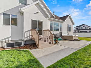 Rear view of house with a hot tub, stucco siding, and a patio area