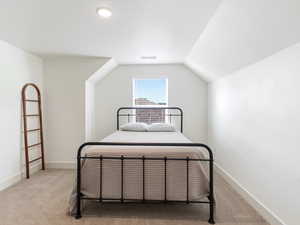 Bedroom with light carpet and vaulted ceiling