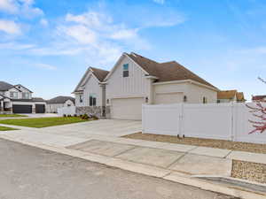 Modern farmhouse style home featuring a gate, board and batten siding, driveway, stone siding, and a shingled roof
