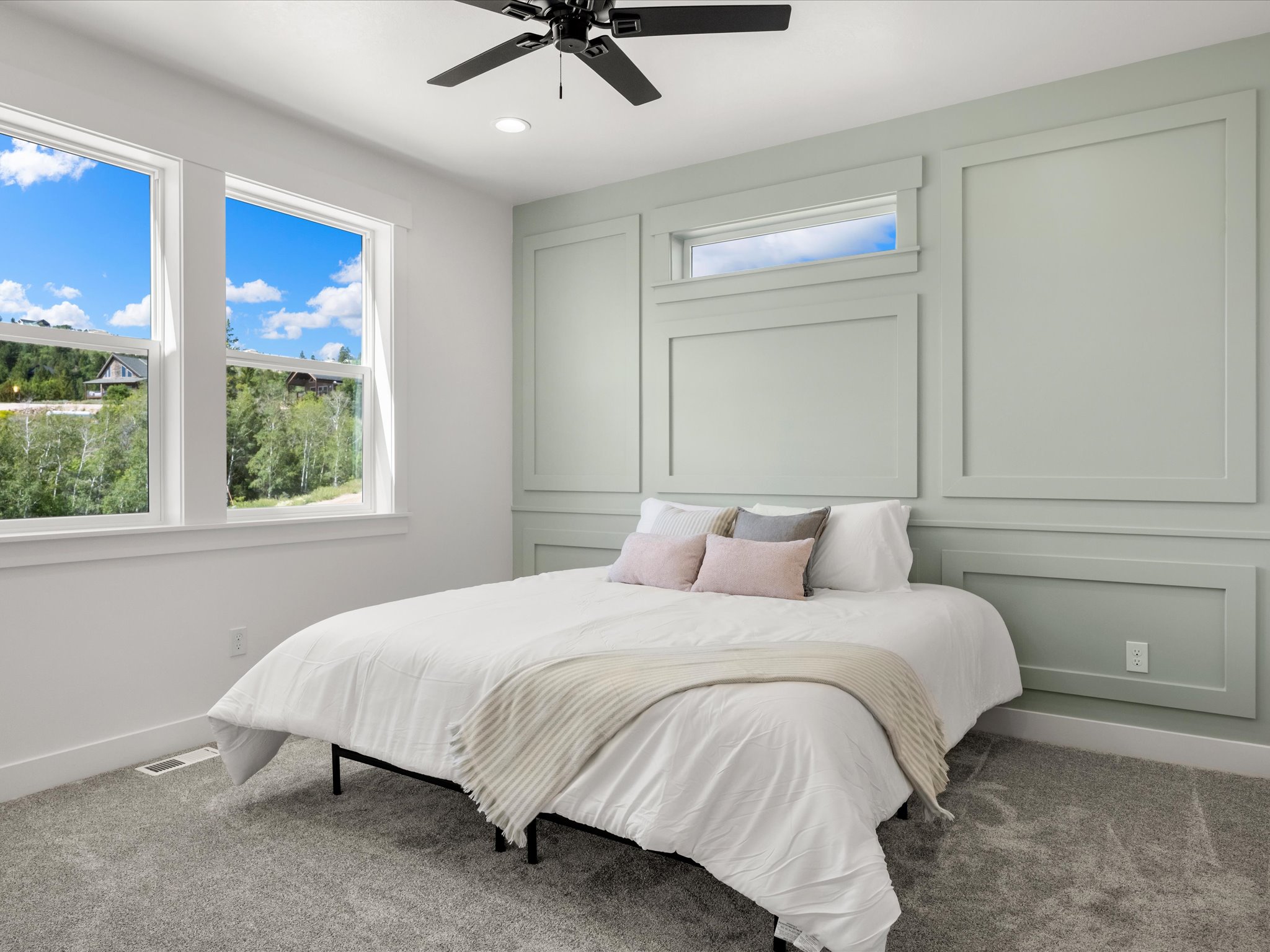 Bedroom featuring decorative wall paneling, a transom window, and dual windows