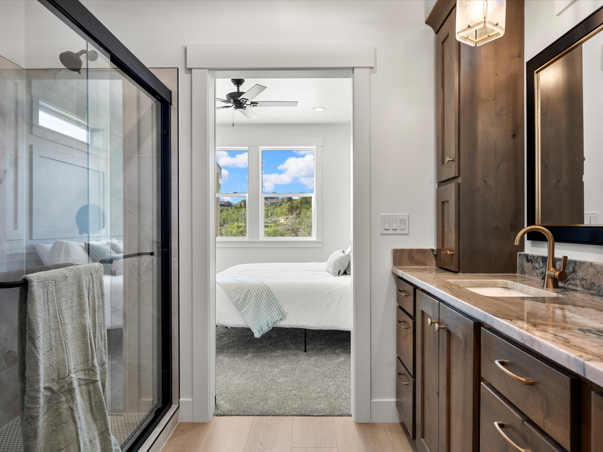Bathroom featuring a glass-enclosed shower with dark trim, a wood vanity with a stone countertop and integrated sink, and an overhead light fixture