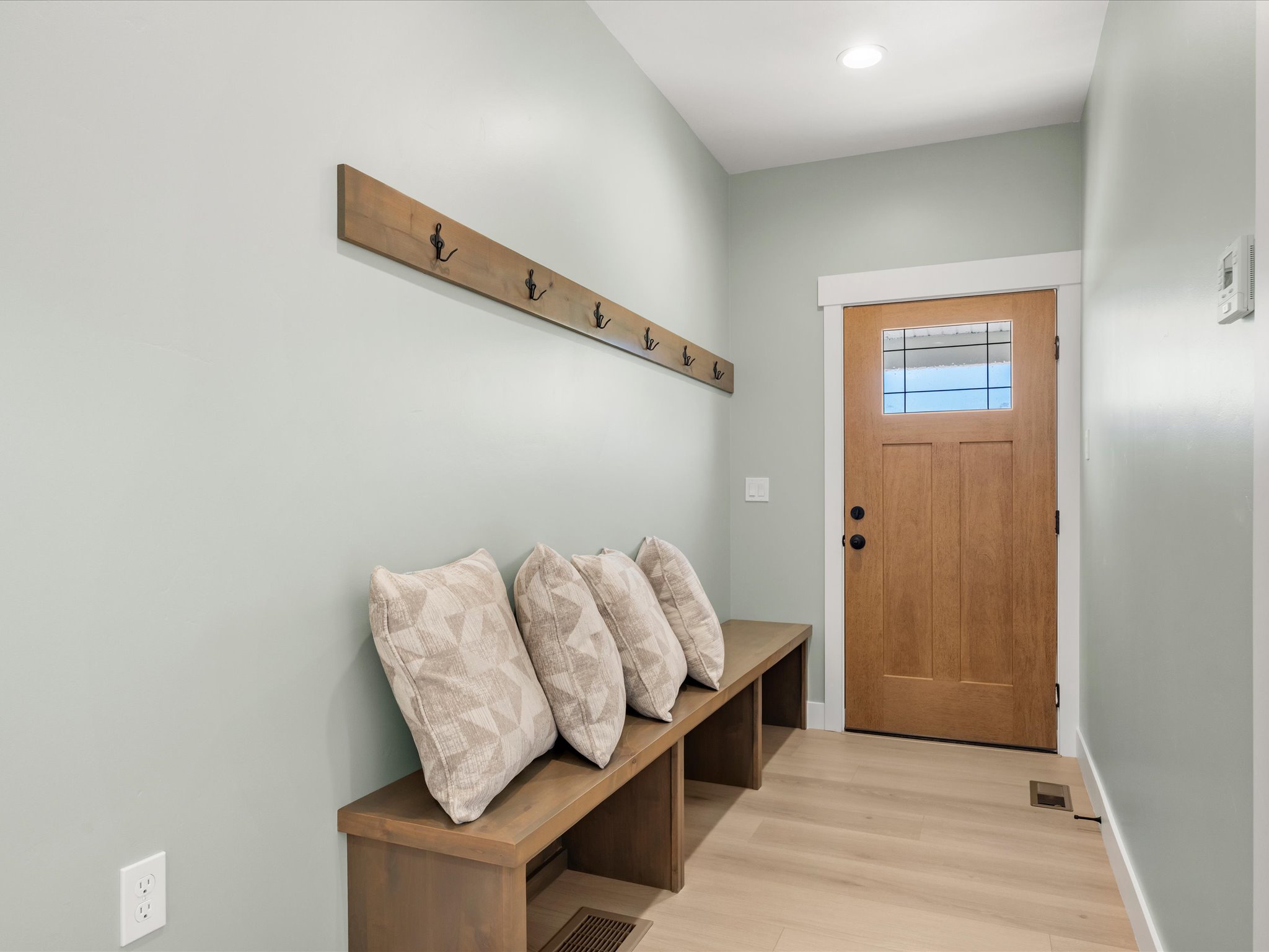 Entryway featuring a solid wood door with a clear glass insert, a built-in wood bench, and light wood-finish flooring