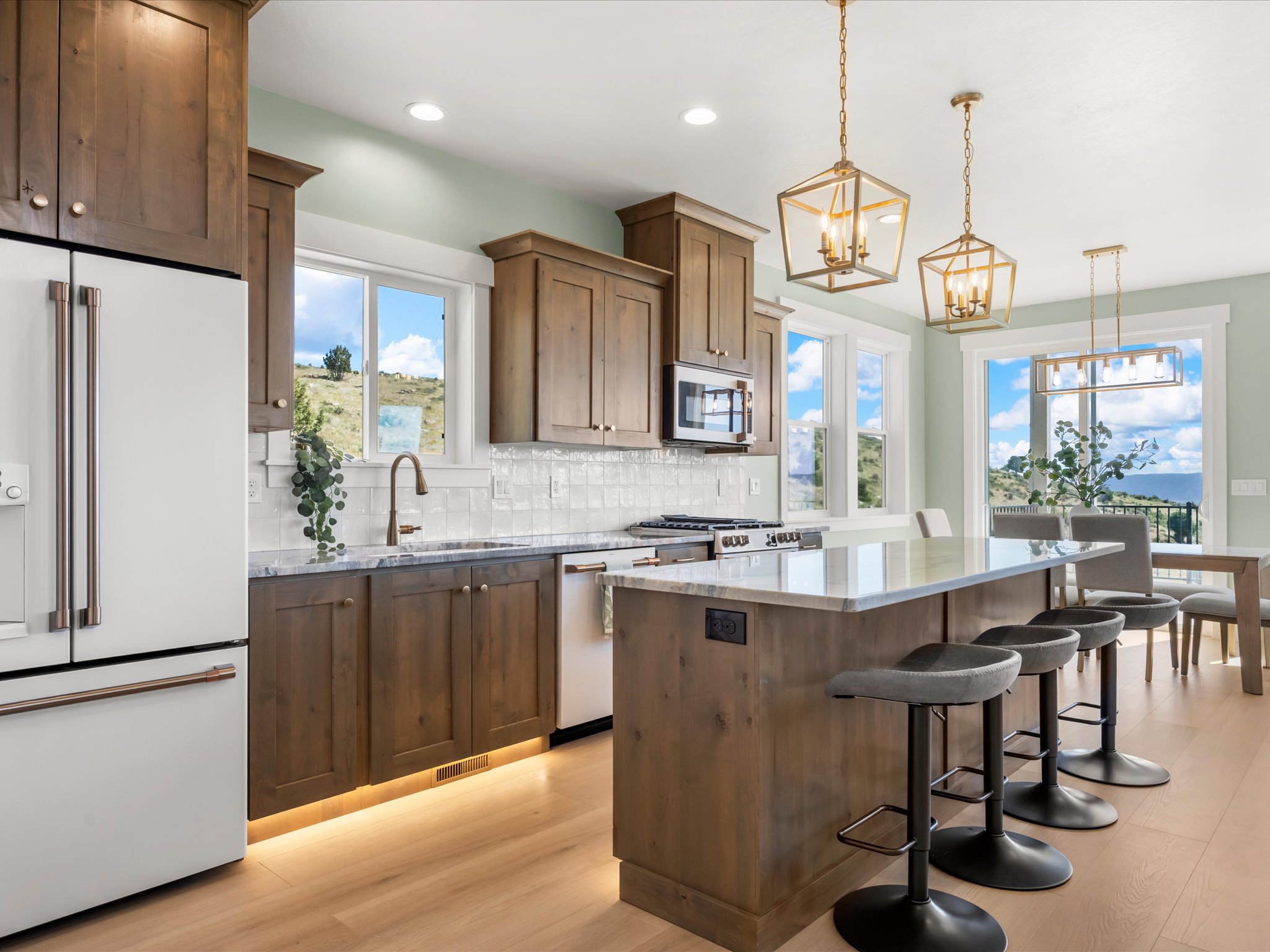 Gourmet kitchen featuring a large central island with seating, wood-finish cabinetry, light-toned wood-finish flooring, and a subway tile backsplash