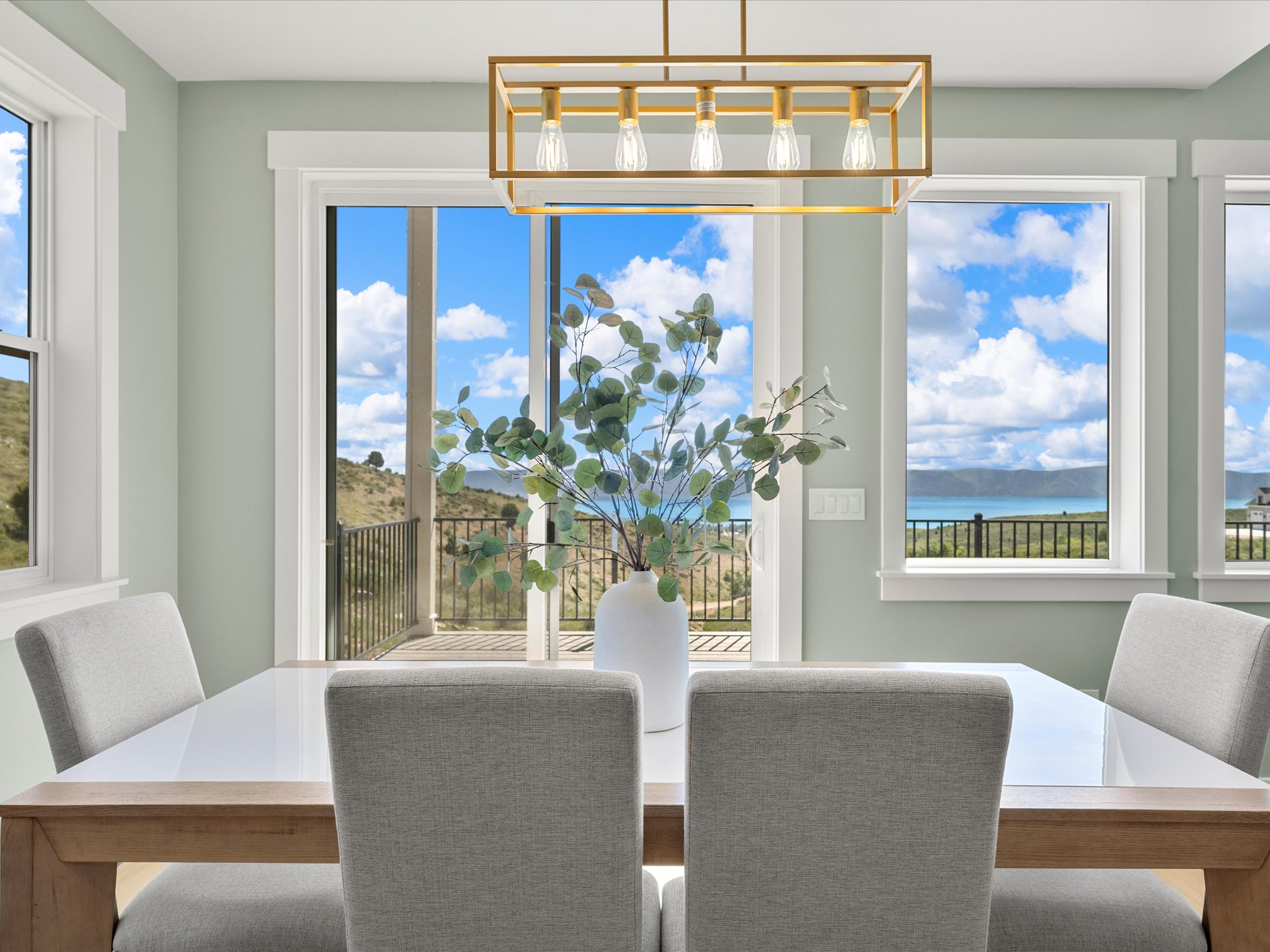 Dining area featuring a modern linear chandelier, light wood-finish table, and upholstered chairs