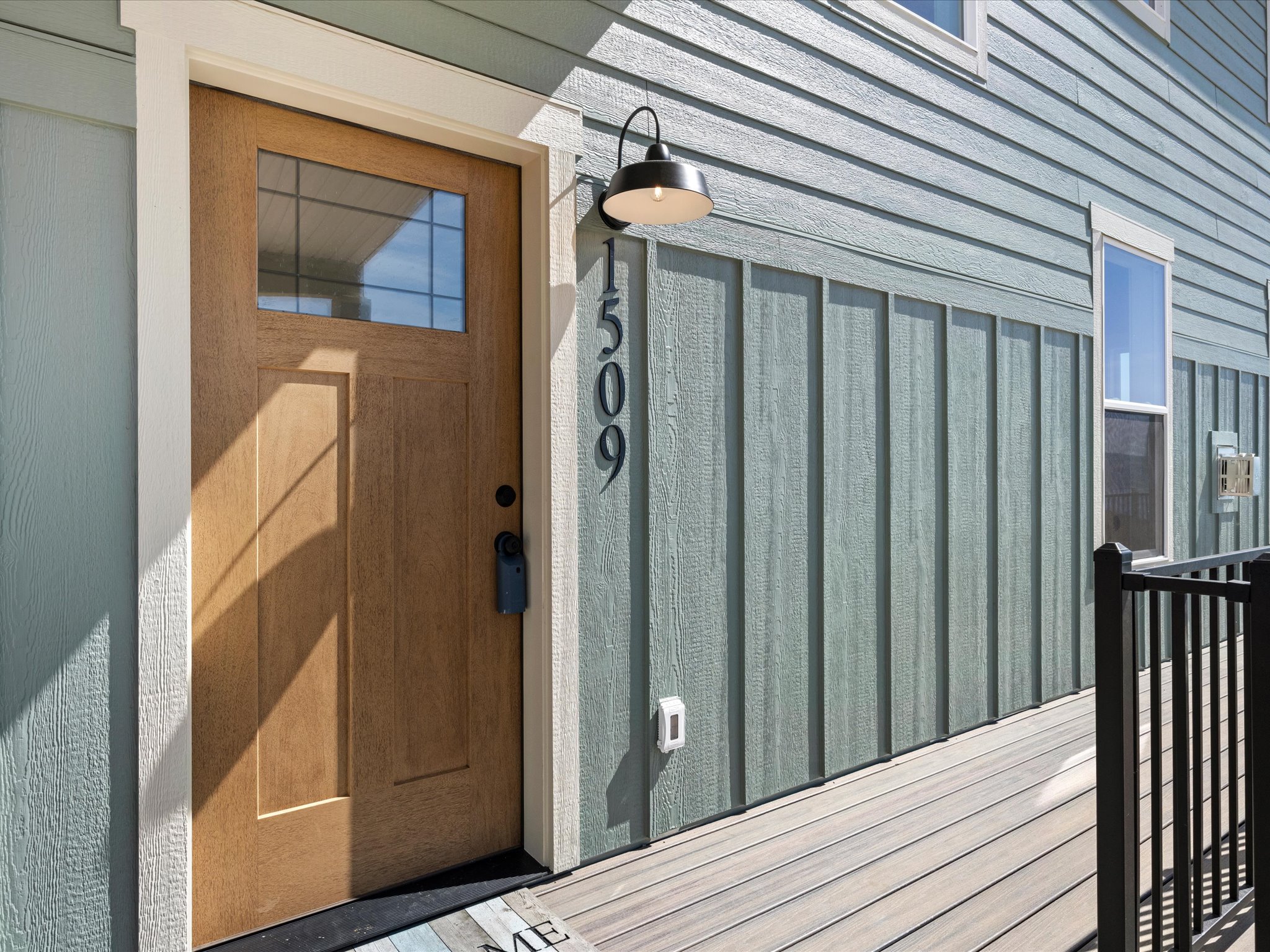 Wood-finish entry door with clear glass transom, framed by white trim