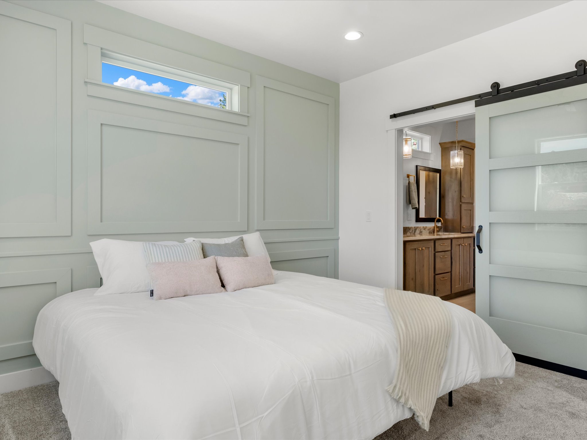 Bedroom featuring wainscoting and a transom window, with a barn door leading to a bathroom