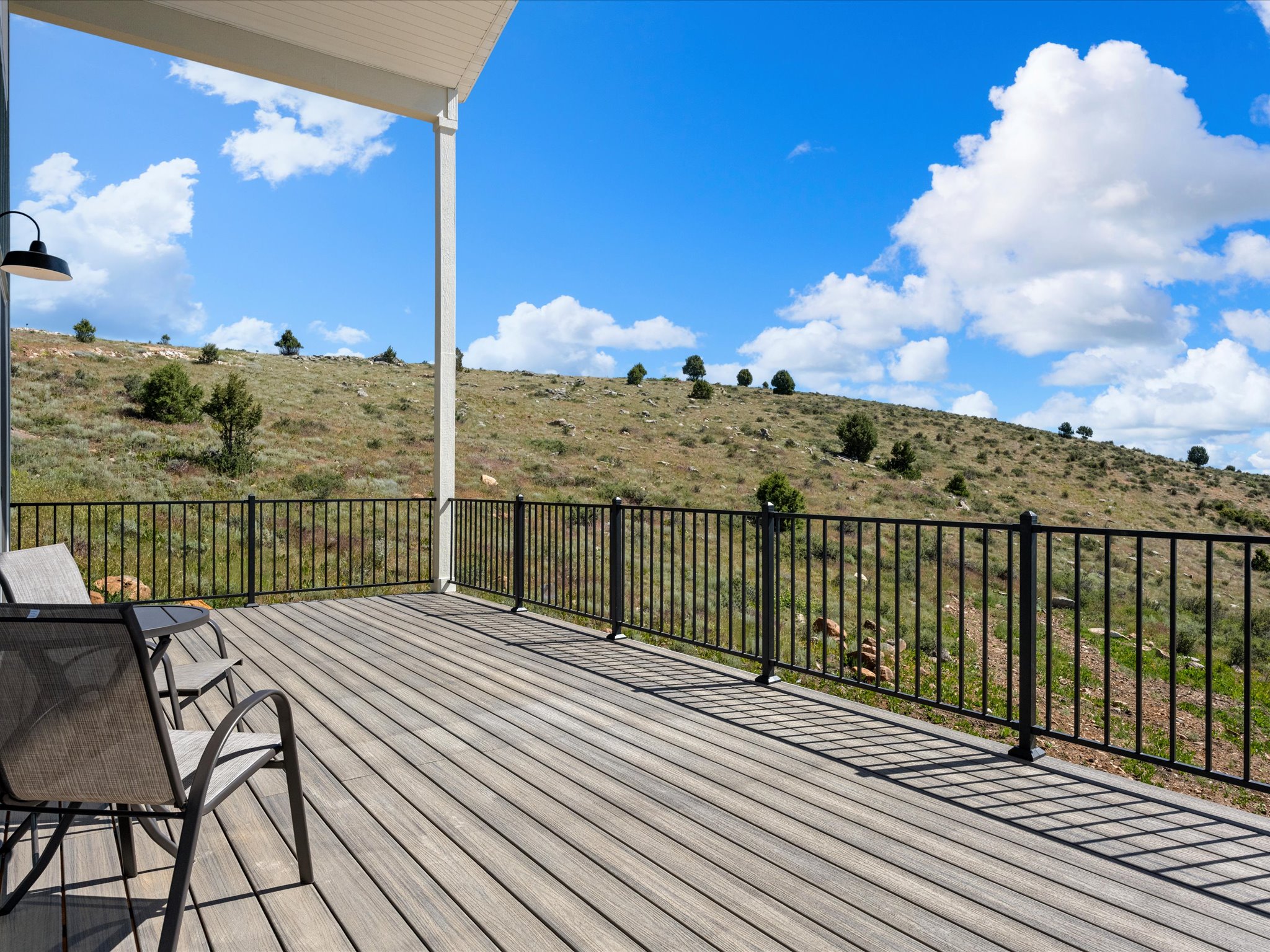 Spacious outdoor deck with wood-finish flooring, black metal railing, and a covered patio area