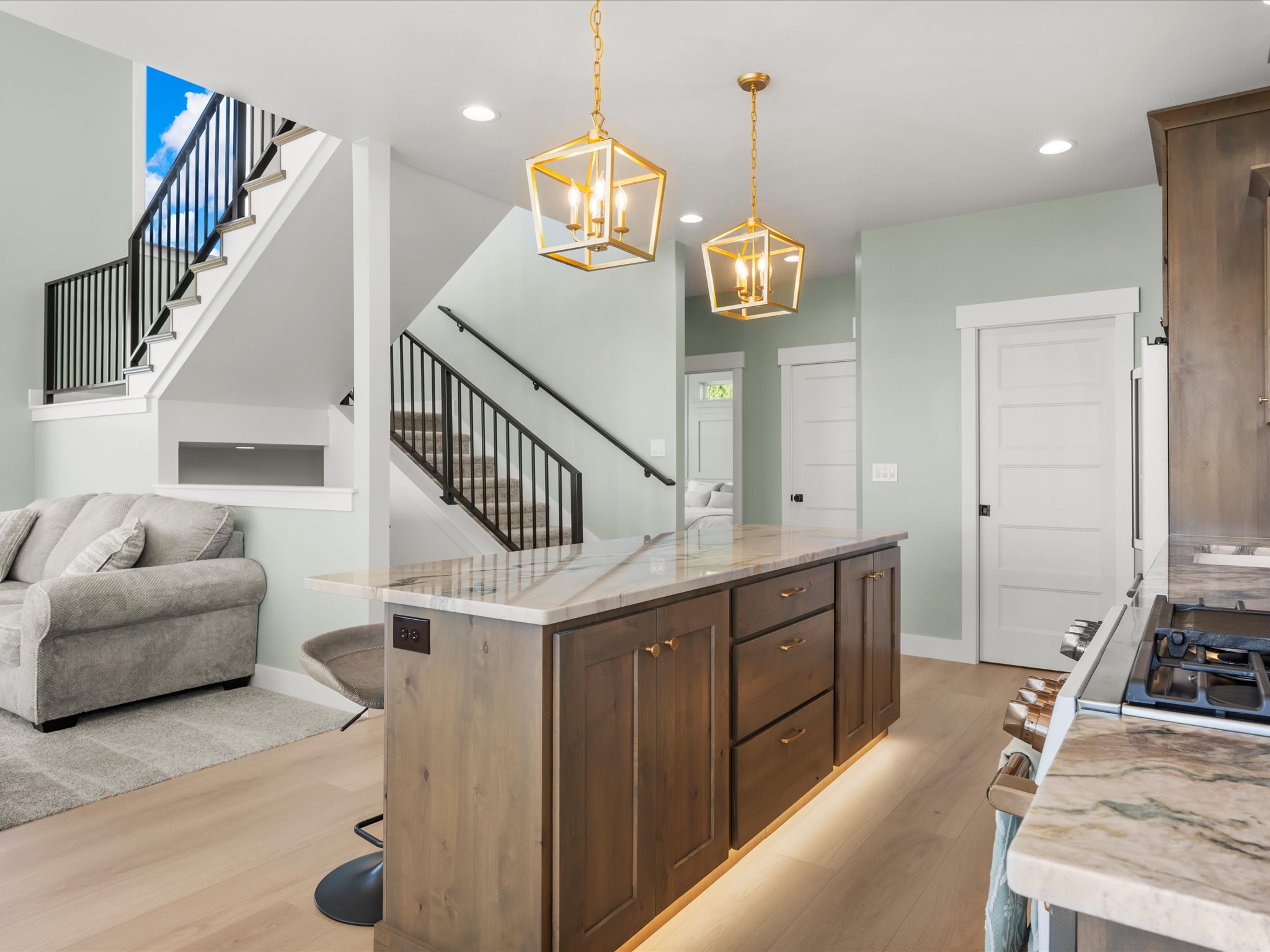 Spacious kitchen island with warm wood-finish cabinetry, under-cabinet lighting, and stone countertops
