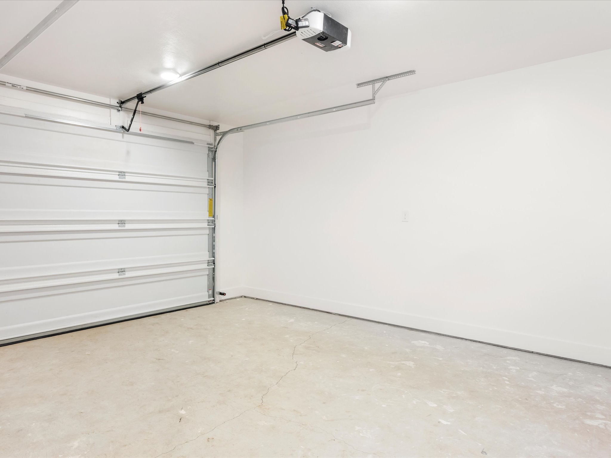 Attached garage featuring a white sectional door, painted interior walls, and a concrete floor