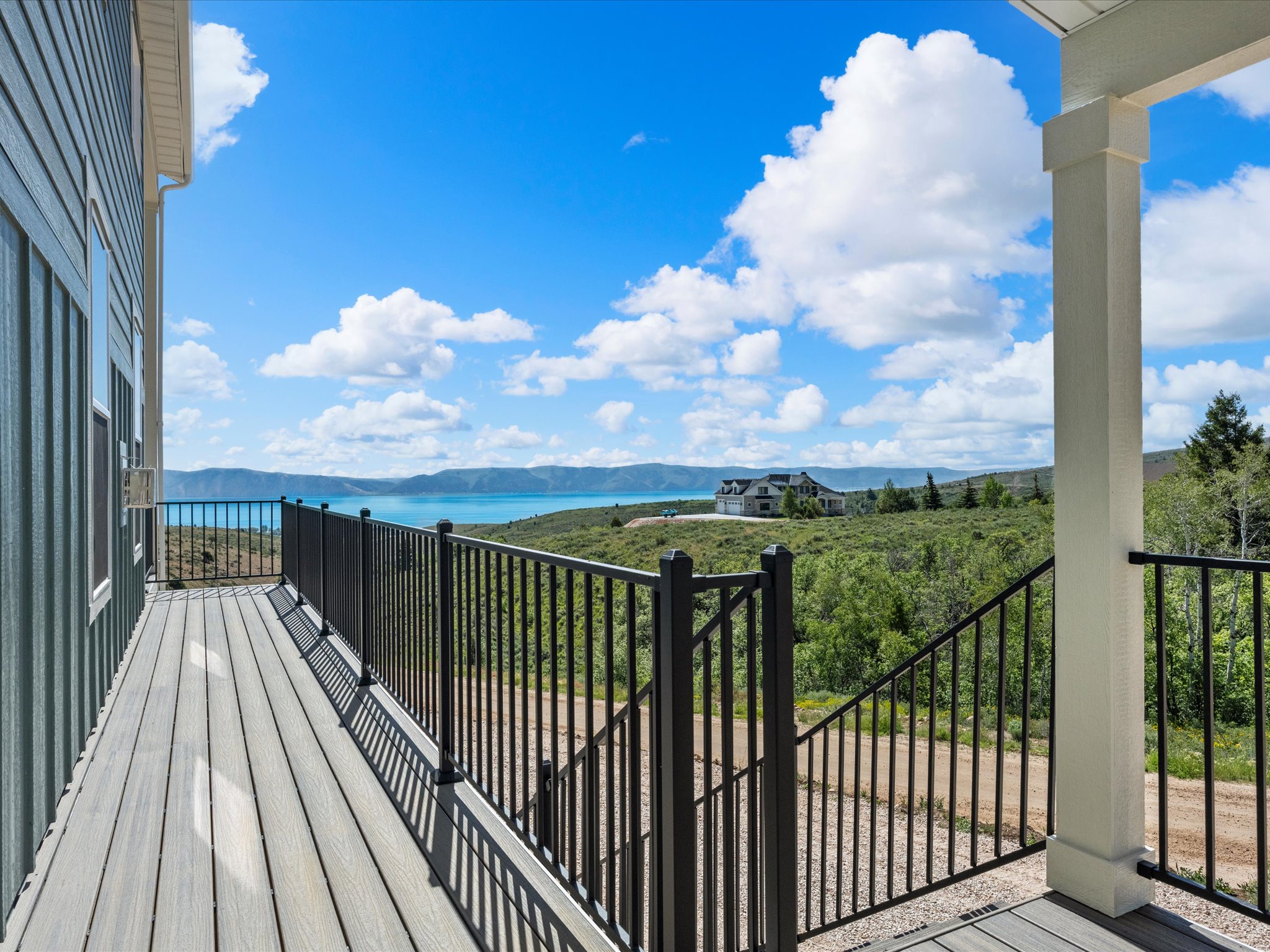 Expansive outdoor deck with composite flooring, black metal railings, and column supports