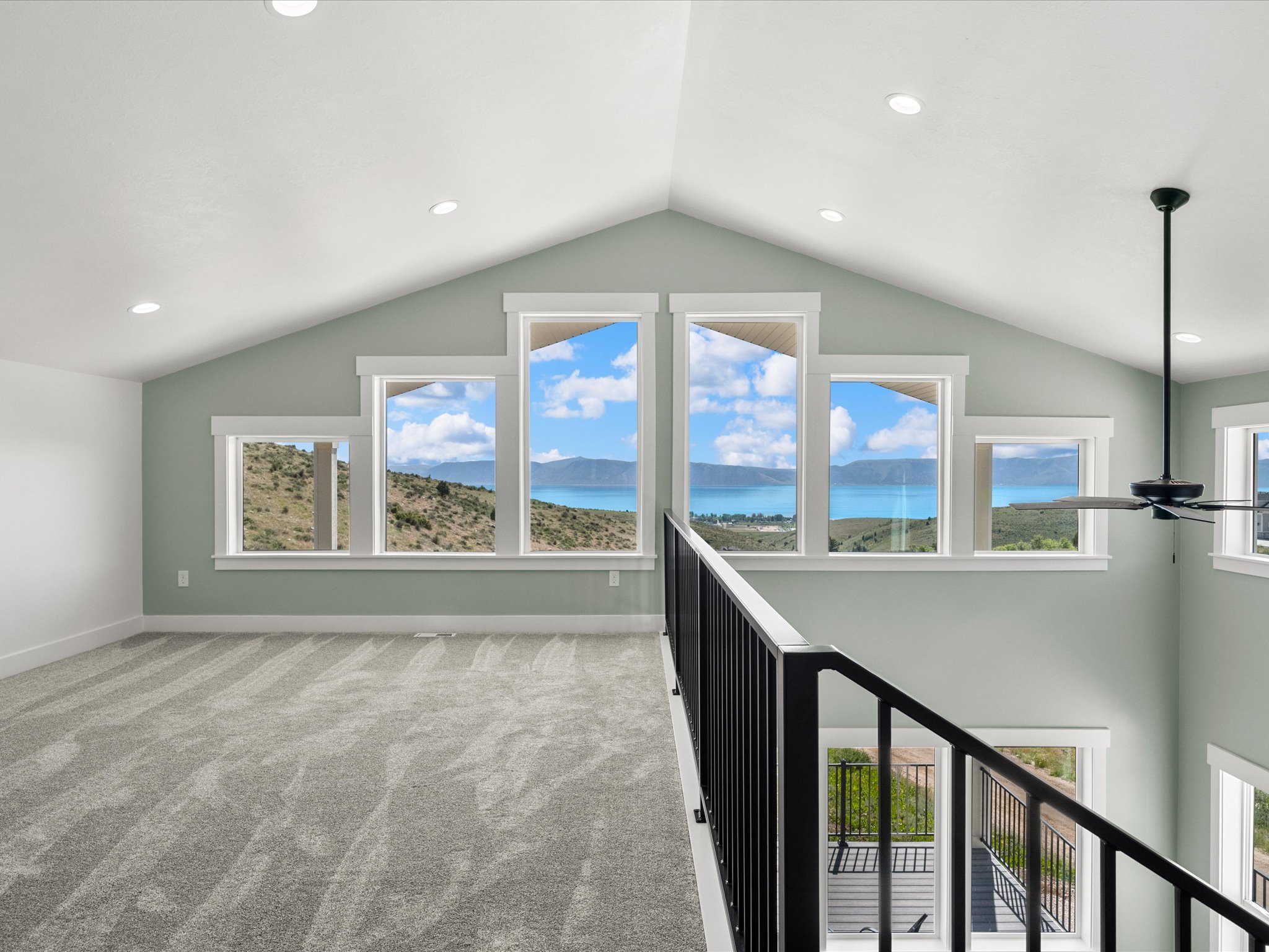Open loft area featuring a vaulted ceiling with recessed lighting, light green wall paint, and gray carpeting