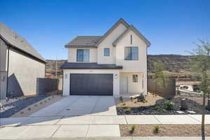 View of front facade with stucco siding, an attached garage, and concrete driveway