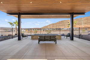 Fenced backyard featuring an outdoor fire pit, a mountain view, and a patio area