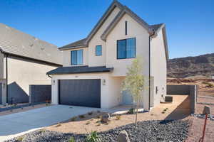 Modern farmhouse featuring concrete driveway, an attached garage, and stucco siding