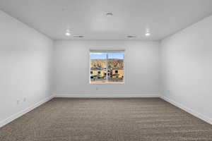 Empty room with dark carpet and recessed lighting