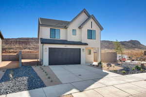 Modern inspired farmhouse with a mountain view, an attached garage, driveway, and stucco siding