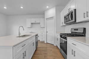 Kitchen featuring stainless steel appliances, an island with sink, recessed lighting, dark wood-style flooring, and white cabinetry