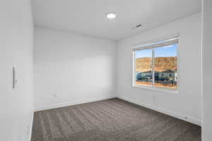 Unfurnished room with dark carpet and baseboards