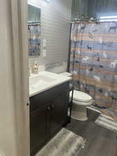 Bathroom featuring vanity, a shower with curtain, dark wood-type flooring, and wood walls