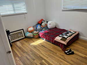 Bedroom with hardwood / wood-style floors and multiple windows