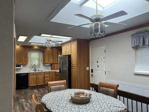 Kitchen with ceiling fan, light countertops, stainless steel fridge with ice dispenser, a textured wall, and wood finish cabinets