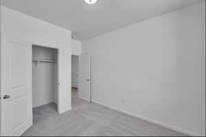 Unfurnished bedroom featuring light colored carpet and a closet