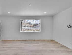 Unfurnished room with light wood finished floors, recessed lighting, and a mountain view