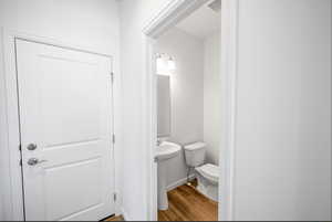 Half bath featuring wood finished floors and toilet