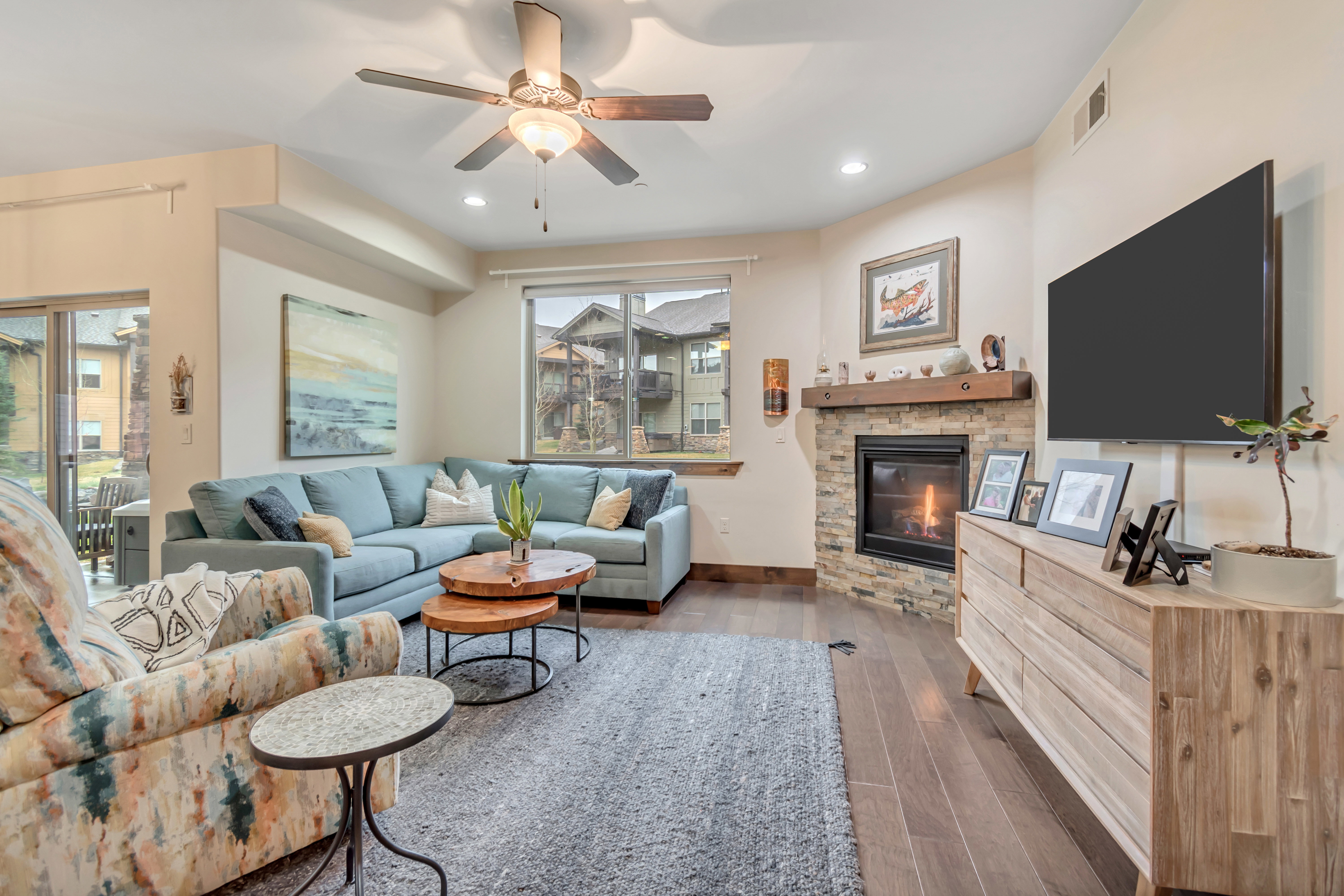 Living room with dark wood-type flooring, a ceiling fan, a fireplace, and recessed lighting