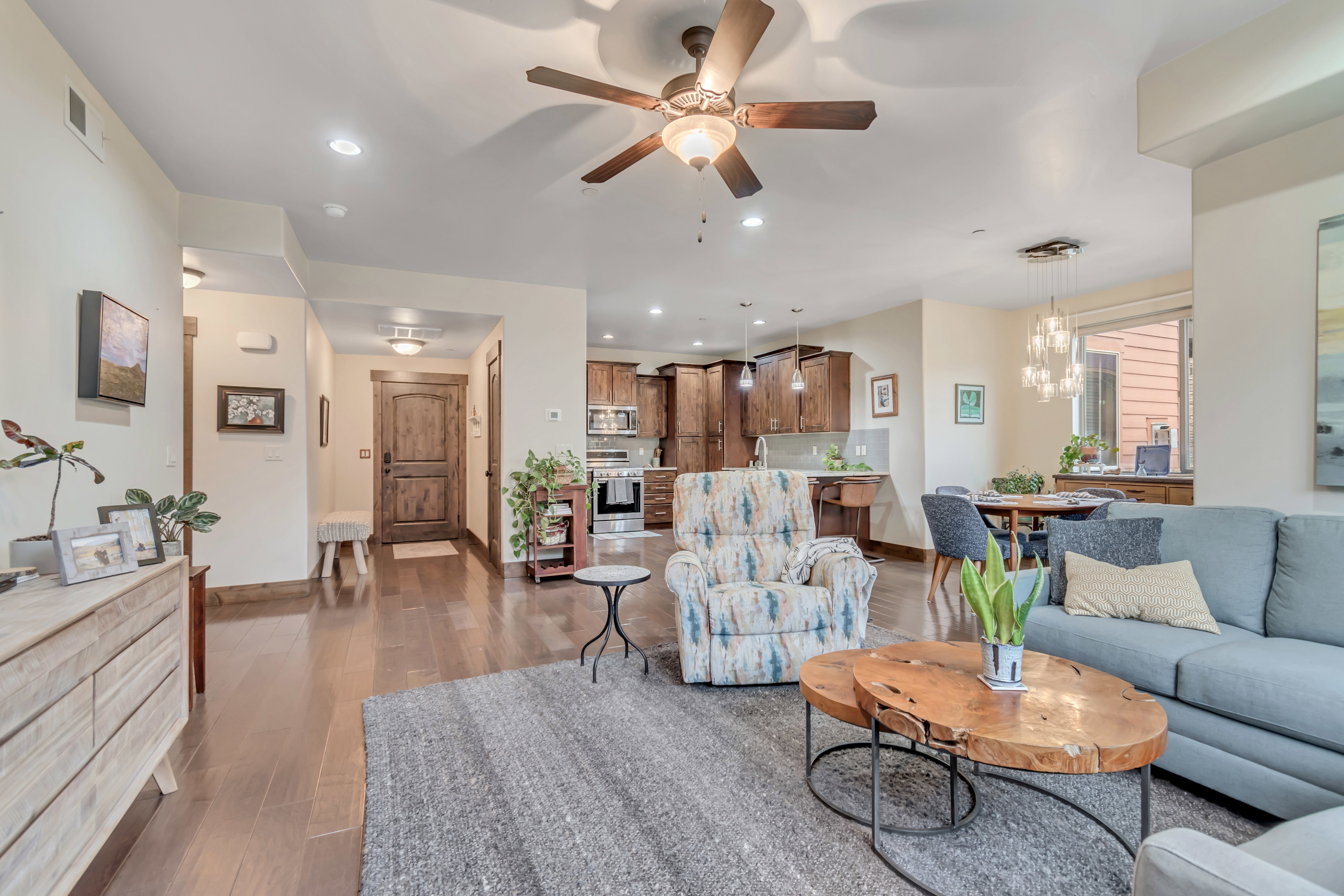 Living room with ceiling fan, light wood-style flooring, and hanging lights