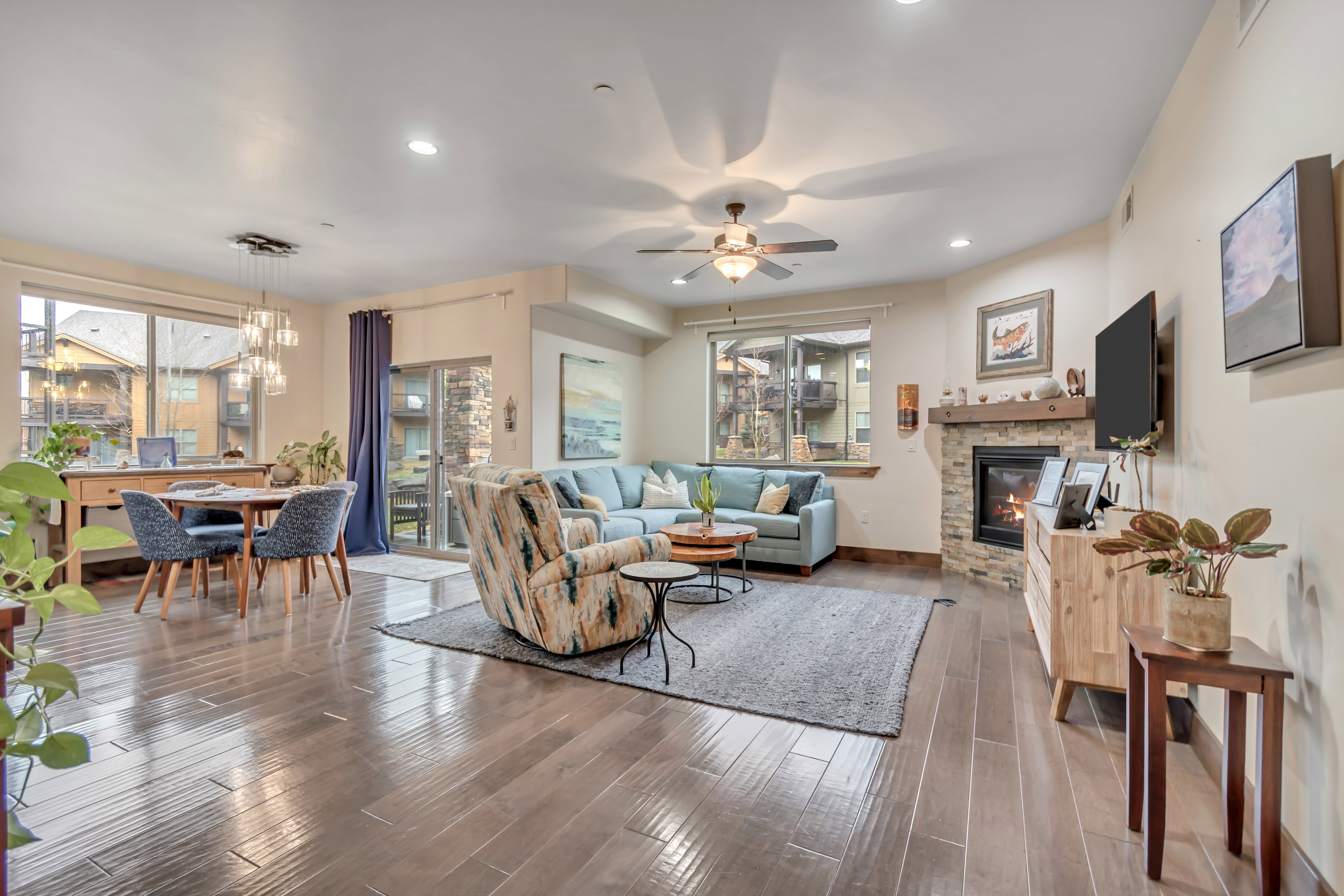 Living room with a ceiling fan, hardwood / wood-style floors, a chandelier, and a fireplace