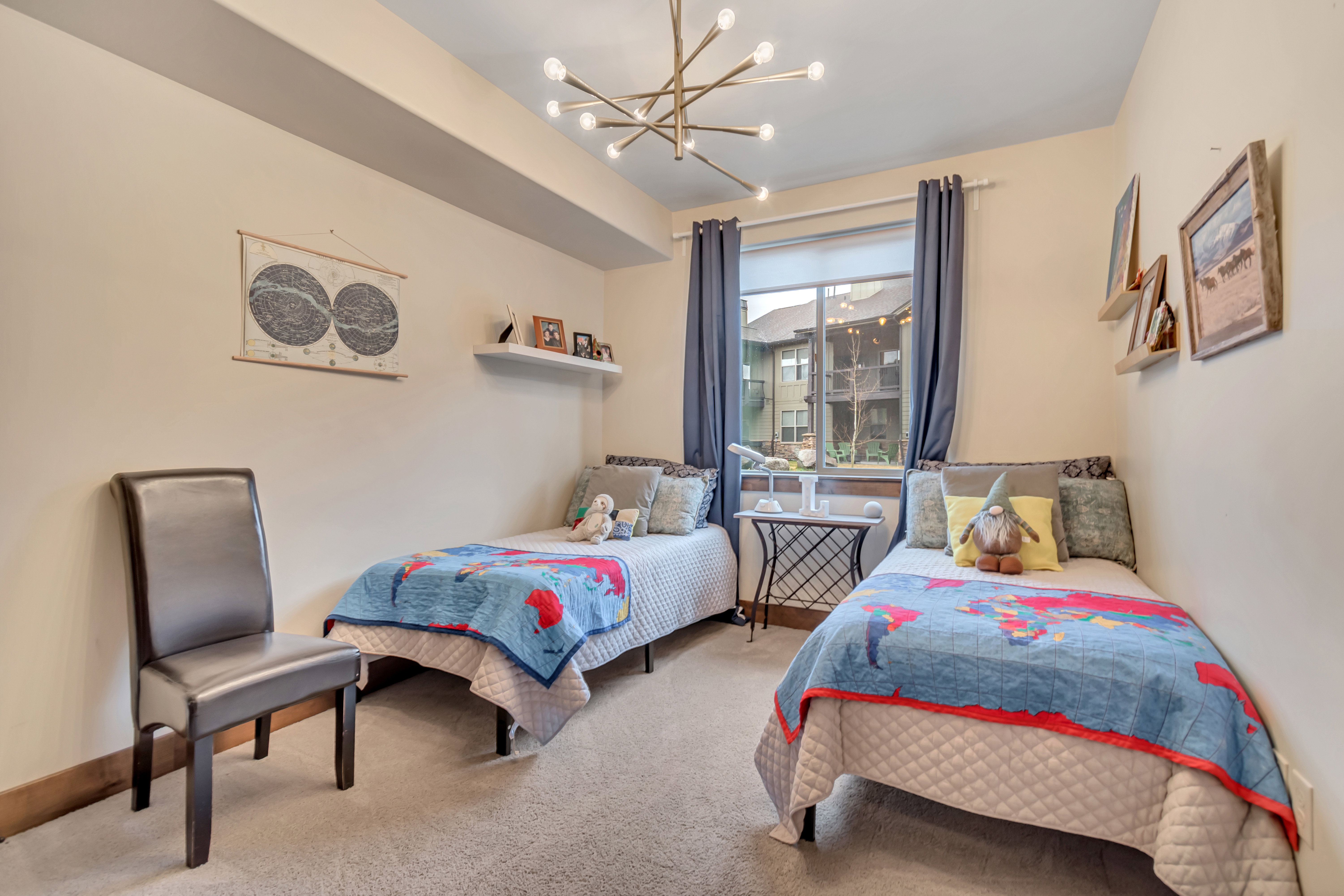 Bedroom with light colored carpet and suspended lighting