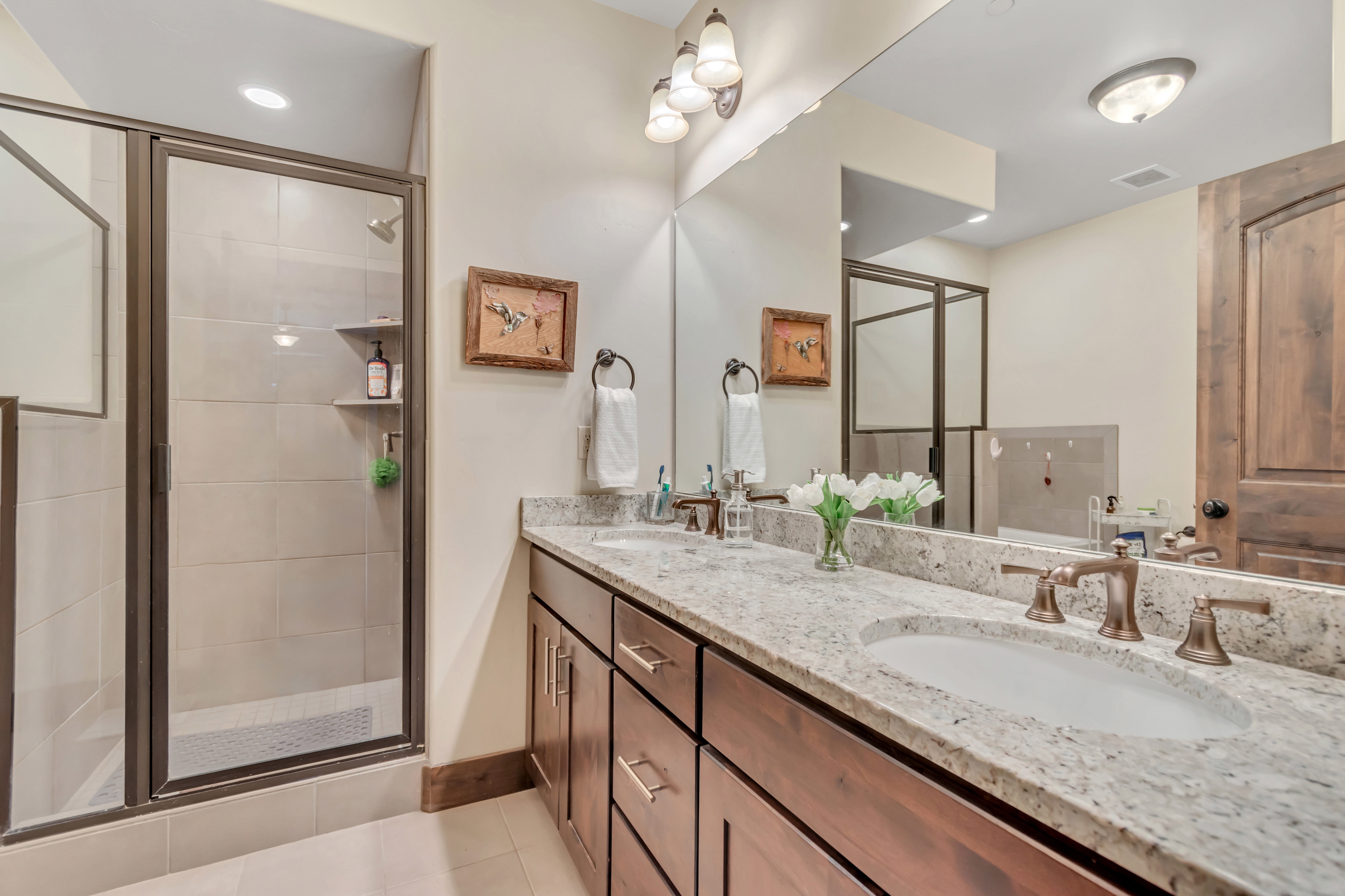 Bathroom featuring double vanity, a shower stall, and light tile patterned flooring