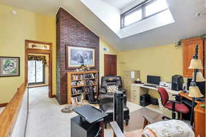 Home office/study featuring light carpet and vaulted ceiling