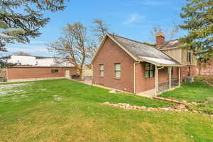 Back of house with brick siding, side yard showing basement access,.