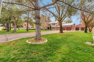 View of front of house with a front yard, a garage, and driveway