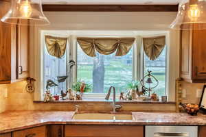 Kitchen bay window featuring wood finish cabinetry, dishwasher, and light stone counters