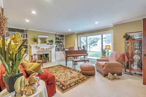 Sitting room with built in features, a high end fireplace, crown molding, and recessed lighting