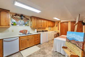 Kitchen with wood finish cabinetry, dishwasher, light countertops, and washer and dryer
