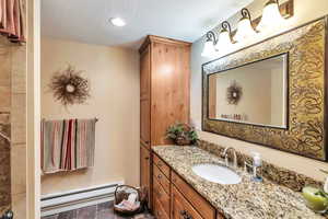 Bathroom featuring a baseboard radiator, vanity, a textured ceiling, and recessed lighting