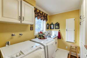 Laundry area featuring cabinet space, washing machine and clothes dryer, and crown molding